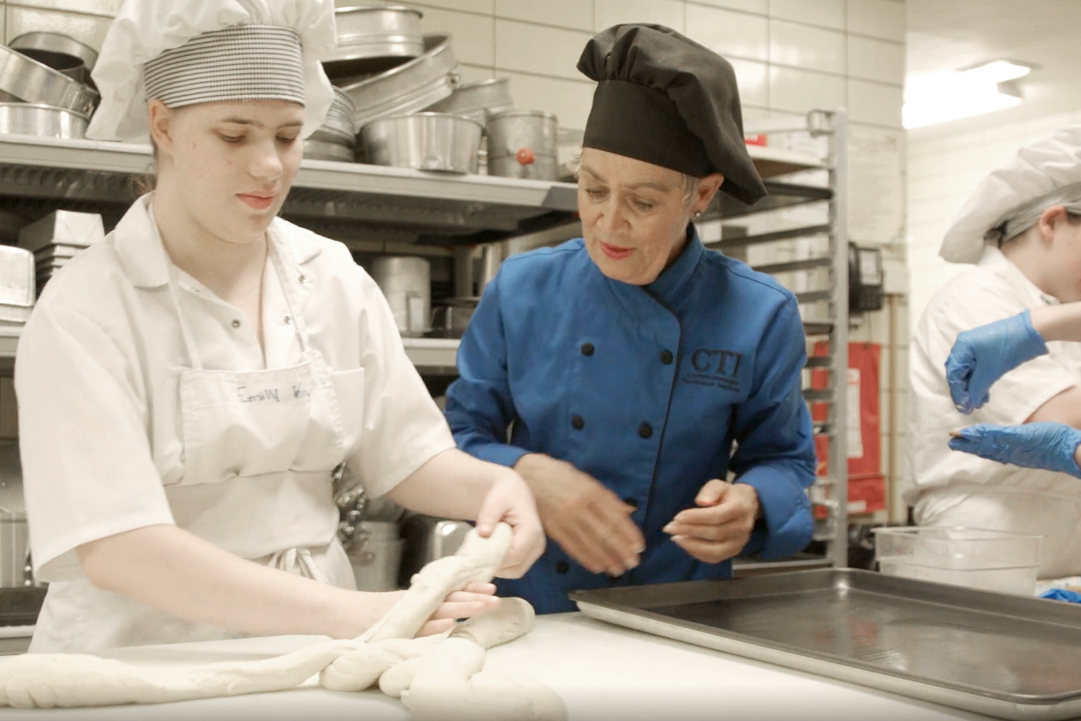 Culinary instructor overseeing student making bread